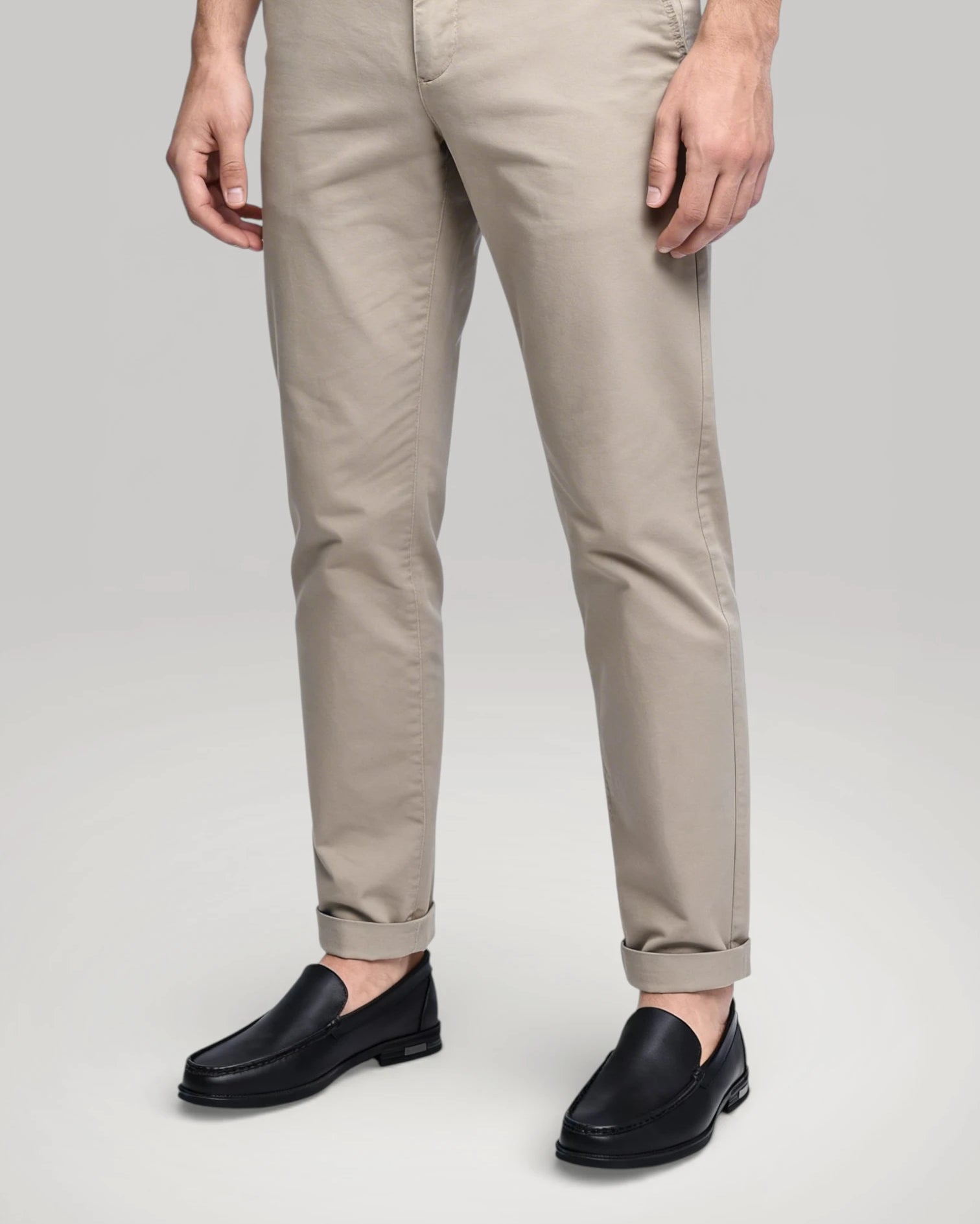 Mocassin Royal homme en cuir noir porté avec un pantalon beige élégant.