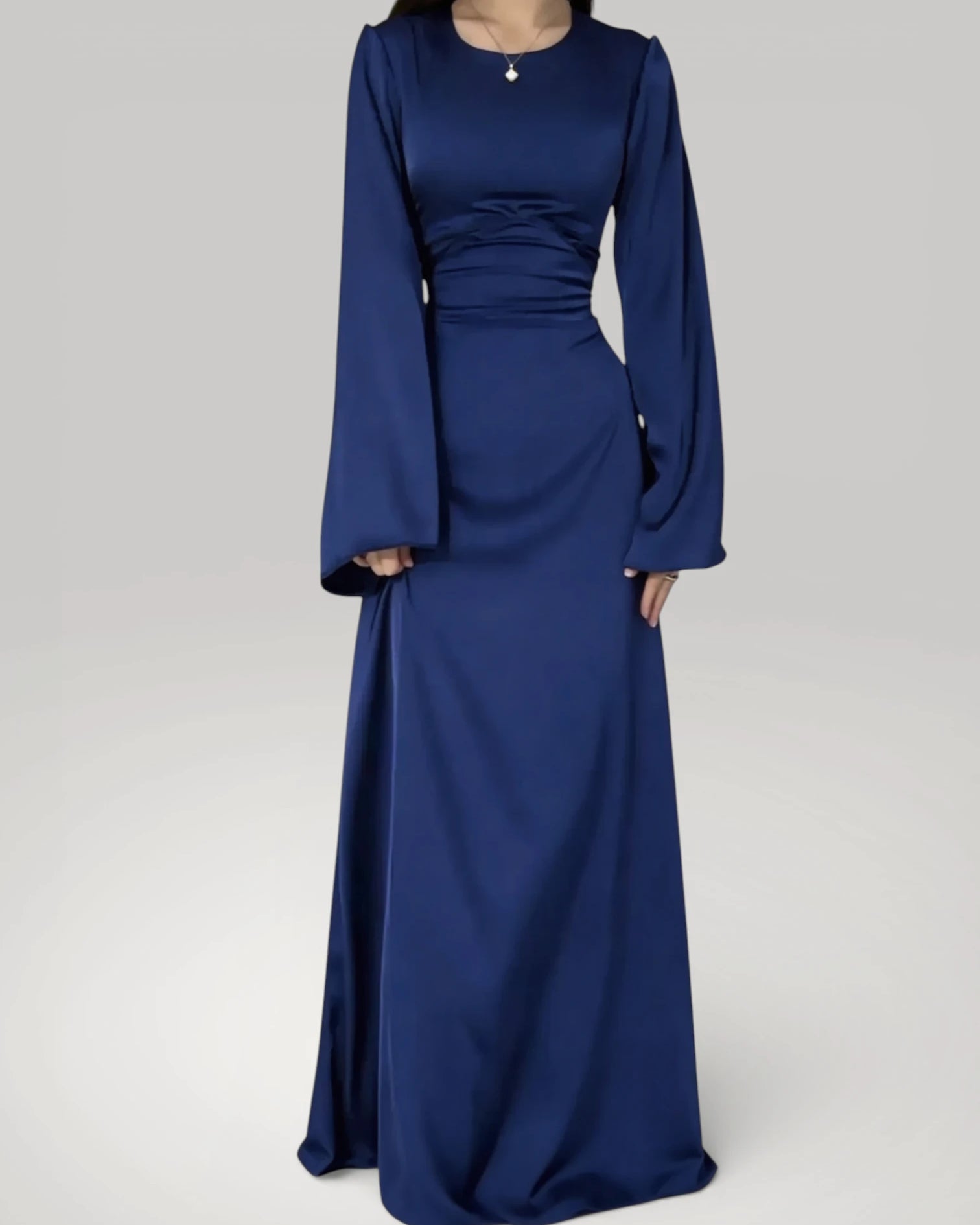 Femme portant la robe longue fluide à taille haute en bleu foncé satiné, style chic.