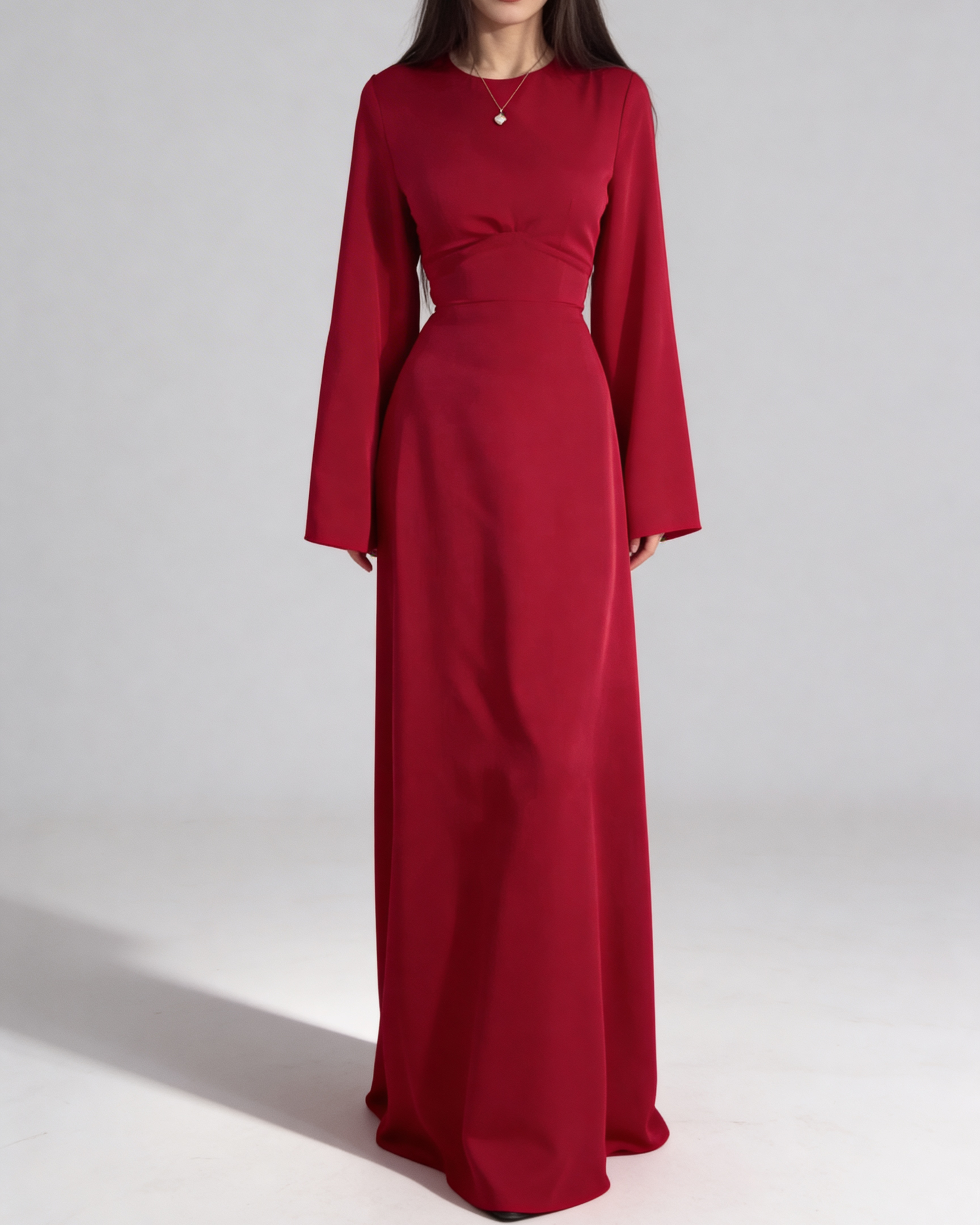 Femme portant la robe longue fluide en satin rouge, coupe cintrée à la taille et manches longues.