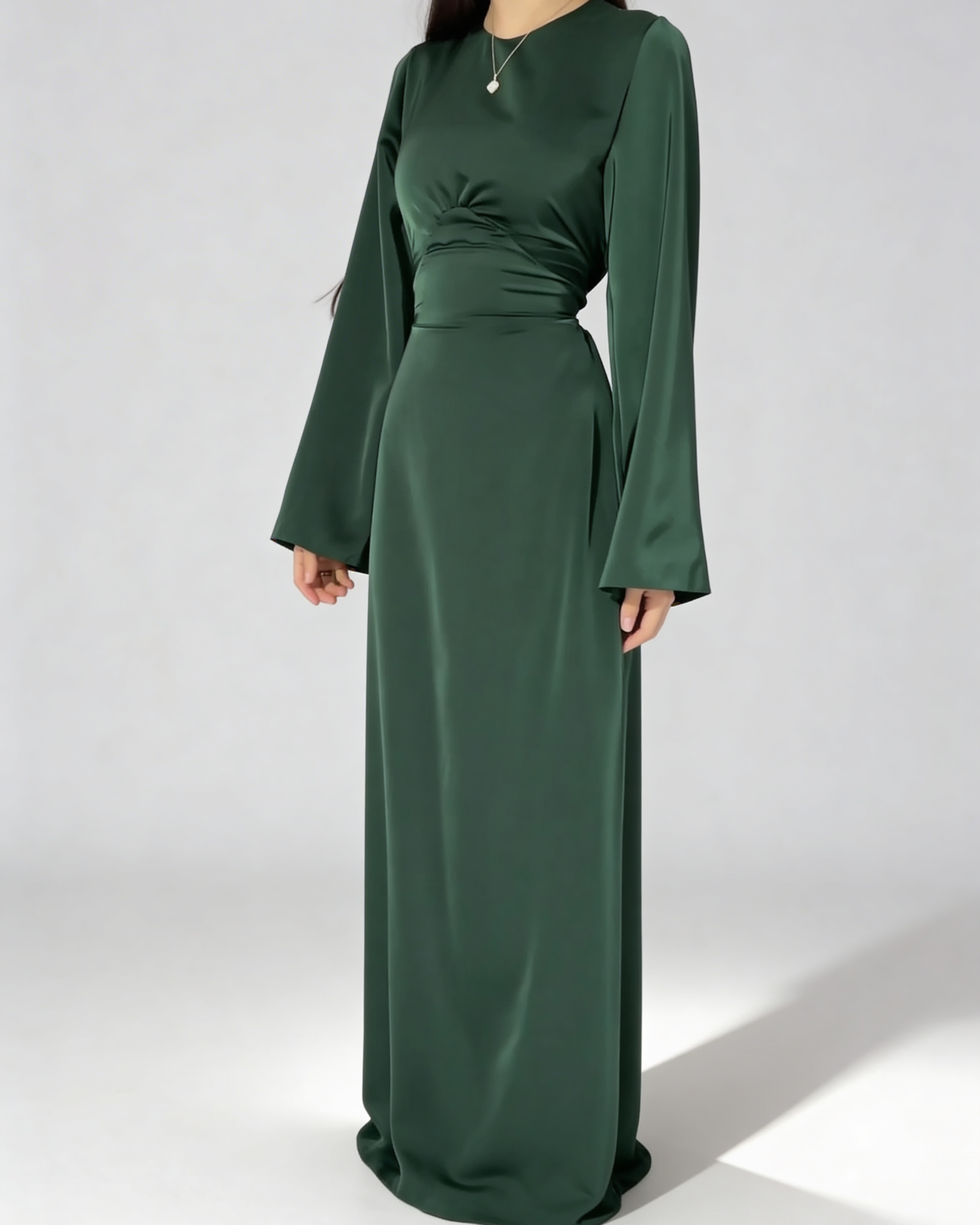 Femme portant la robe longue fluide à taille haute en vert paon satiné, tenue de soirée.