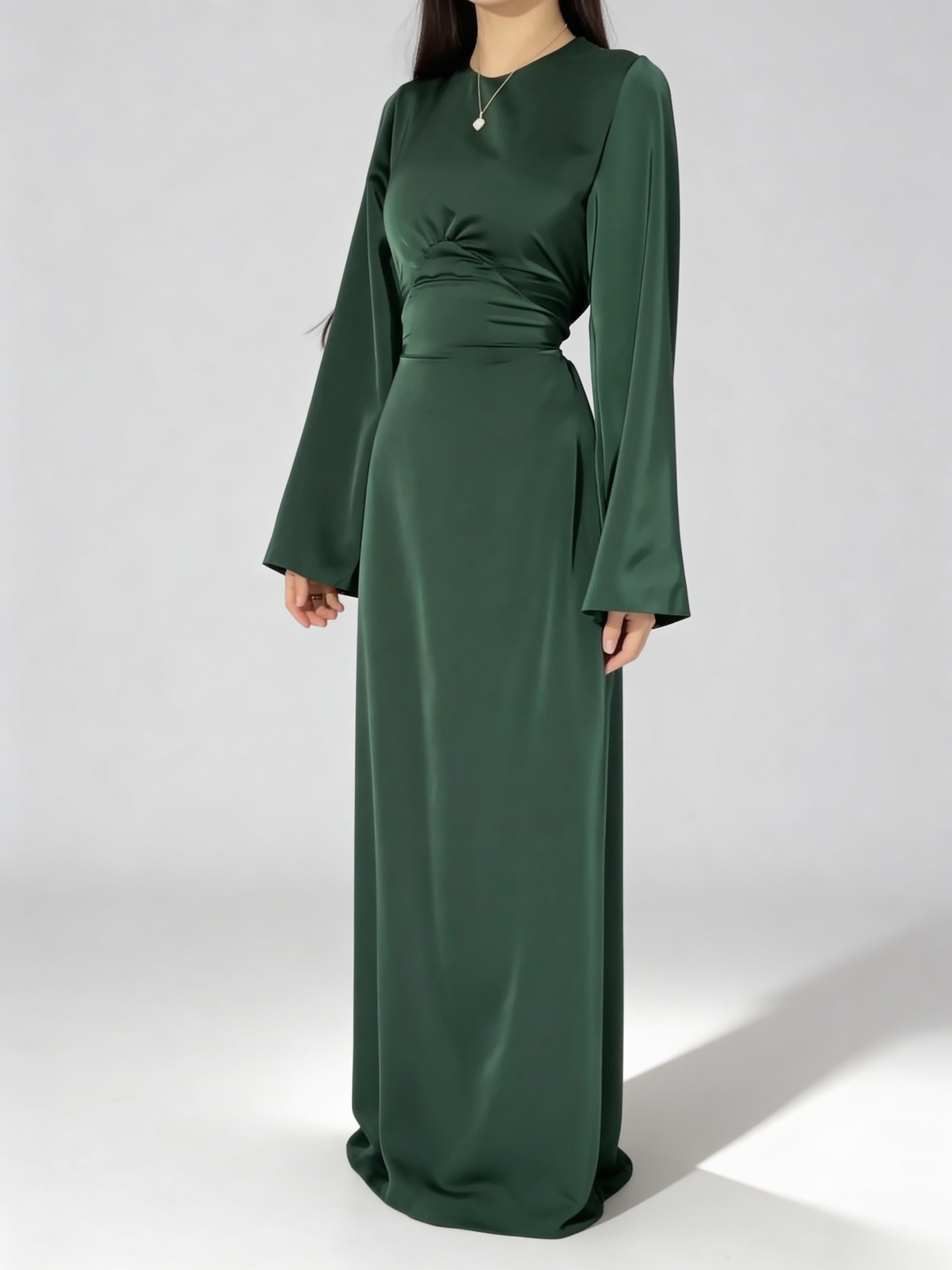 Femme portant la robe longue fluide à taille haute en vert paon satiné, tenue de soirée.