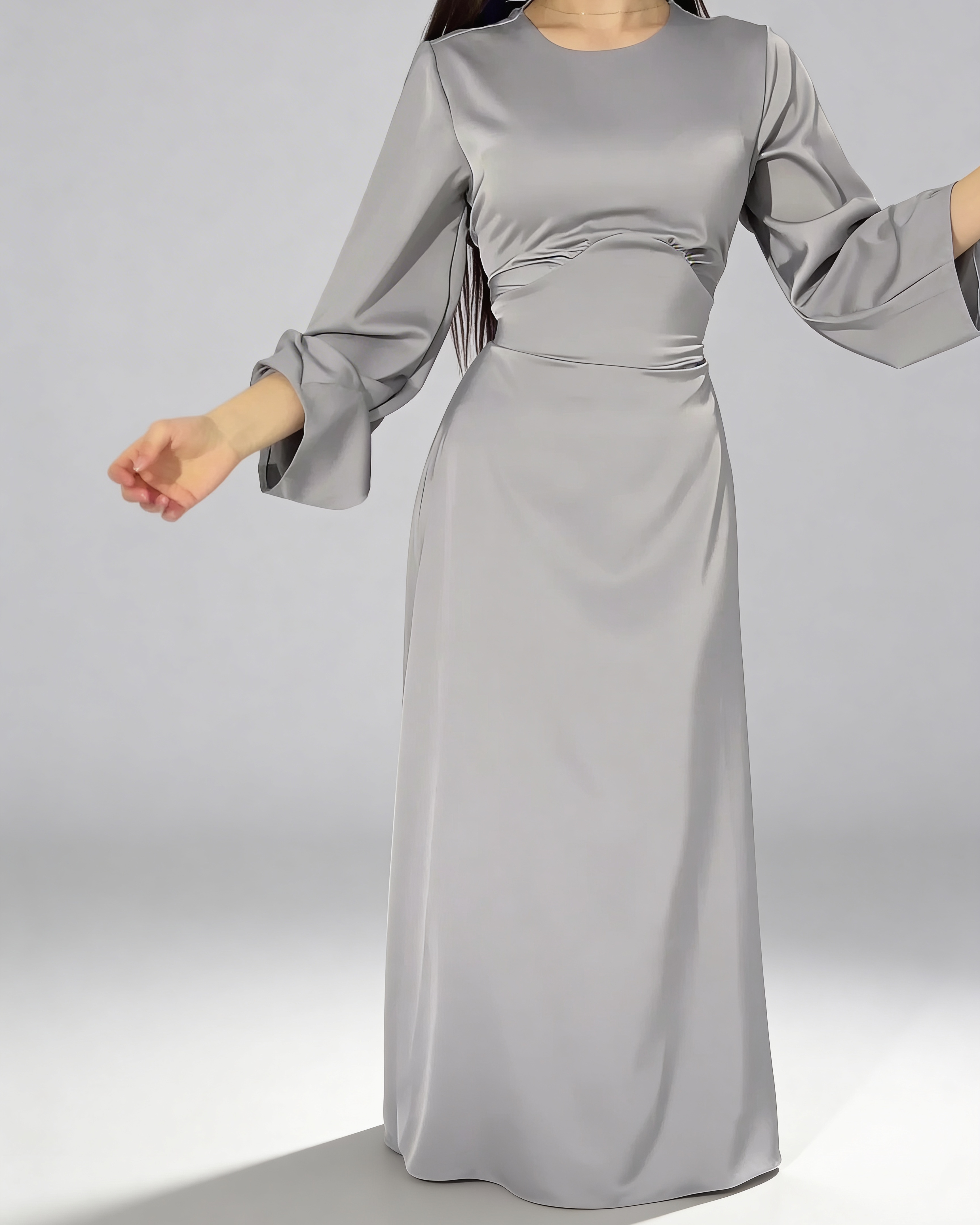 Détail du mouvement fluide de la robe longue en satin gris avec manches larges.