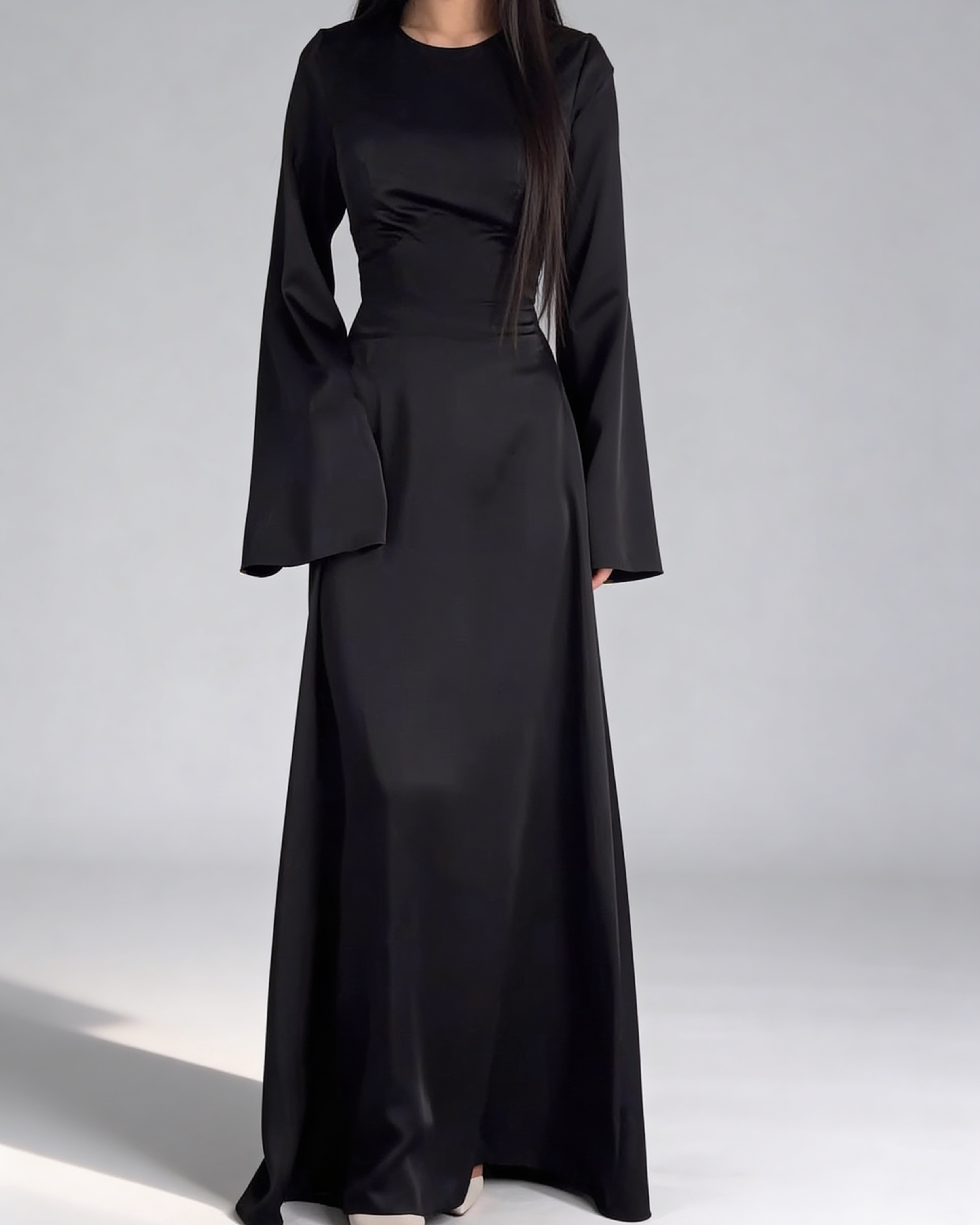 Vue de face de la robe longue fluide pour femme en noir, avec taille ajustée et manches longues.