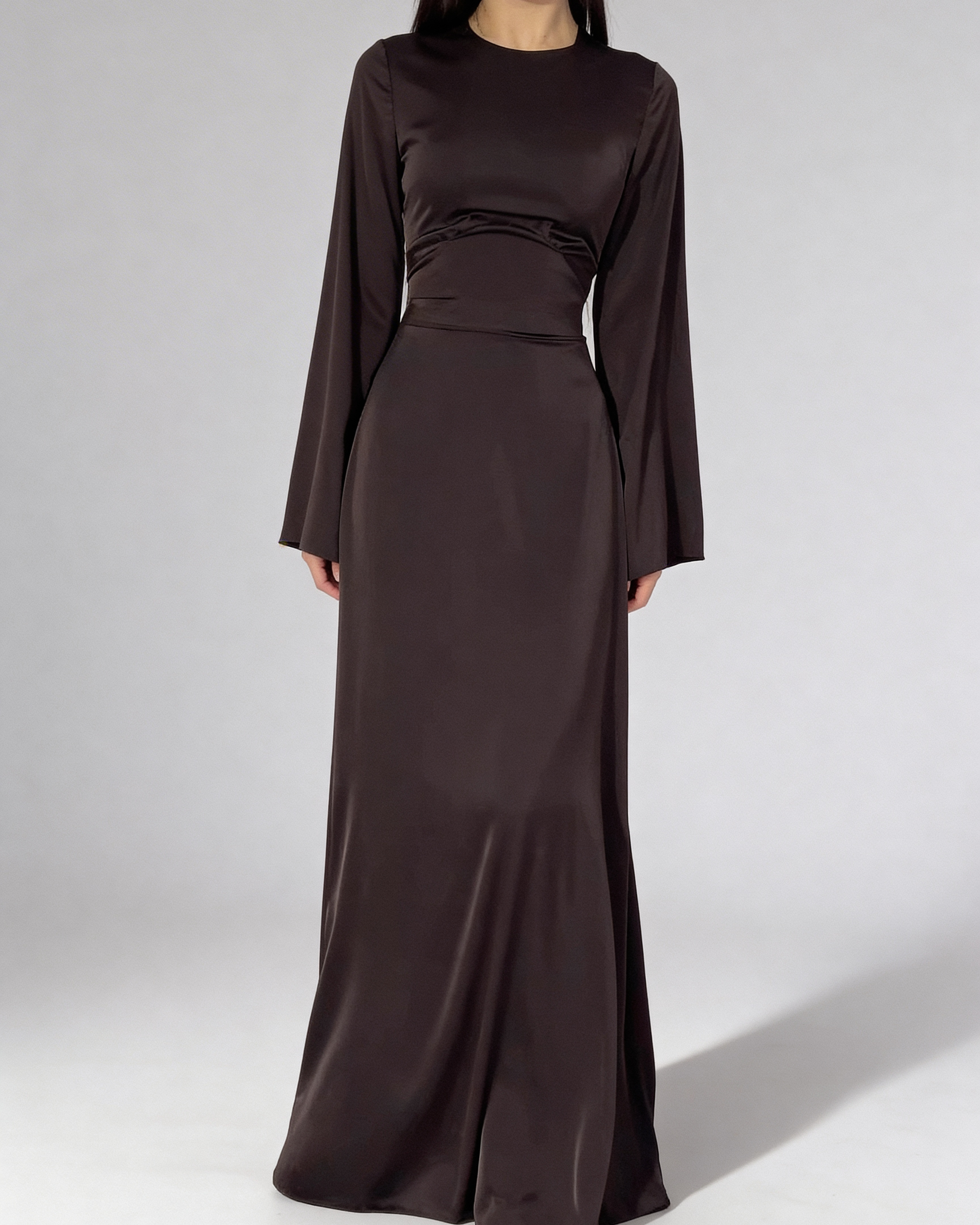 Femme portant la robe longue fluide à taille haute de couleur brun chocolat, coupe élégante.