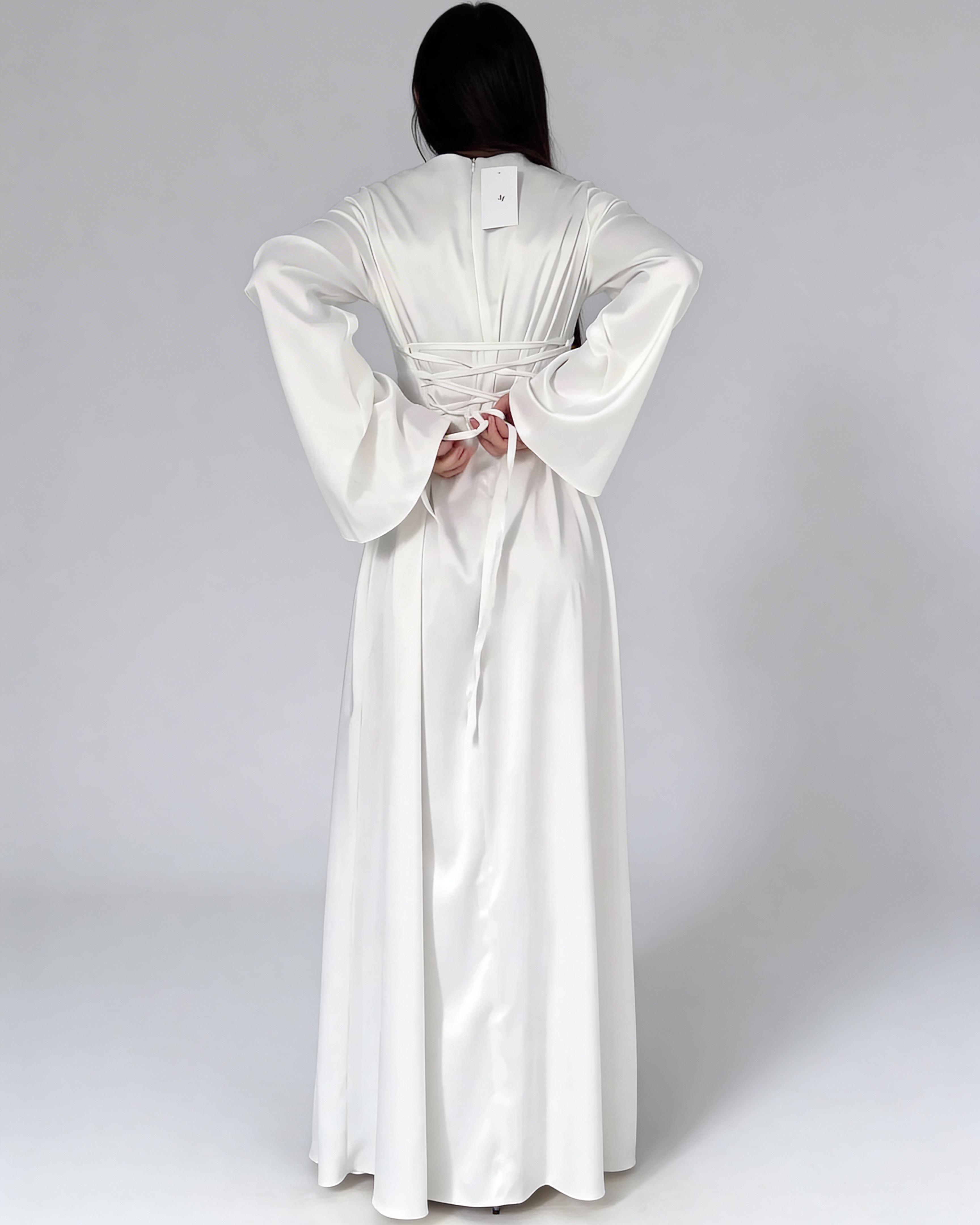 Vue de dos de la robe longue fluide en satin blanc, montrant la coupe fluide et la chute du tissu.
