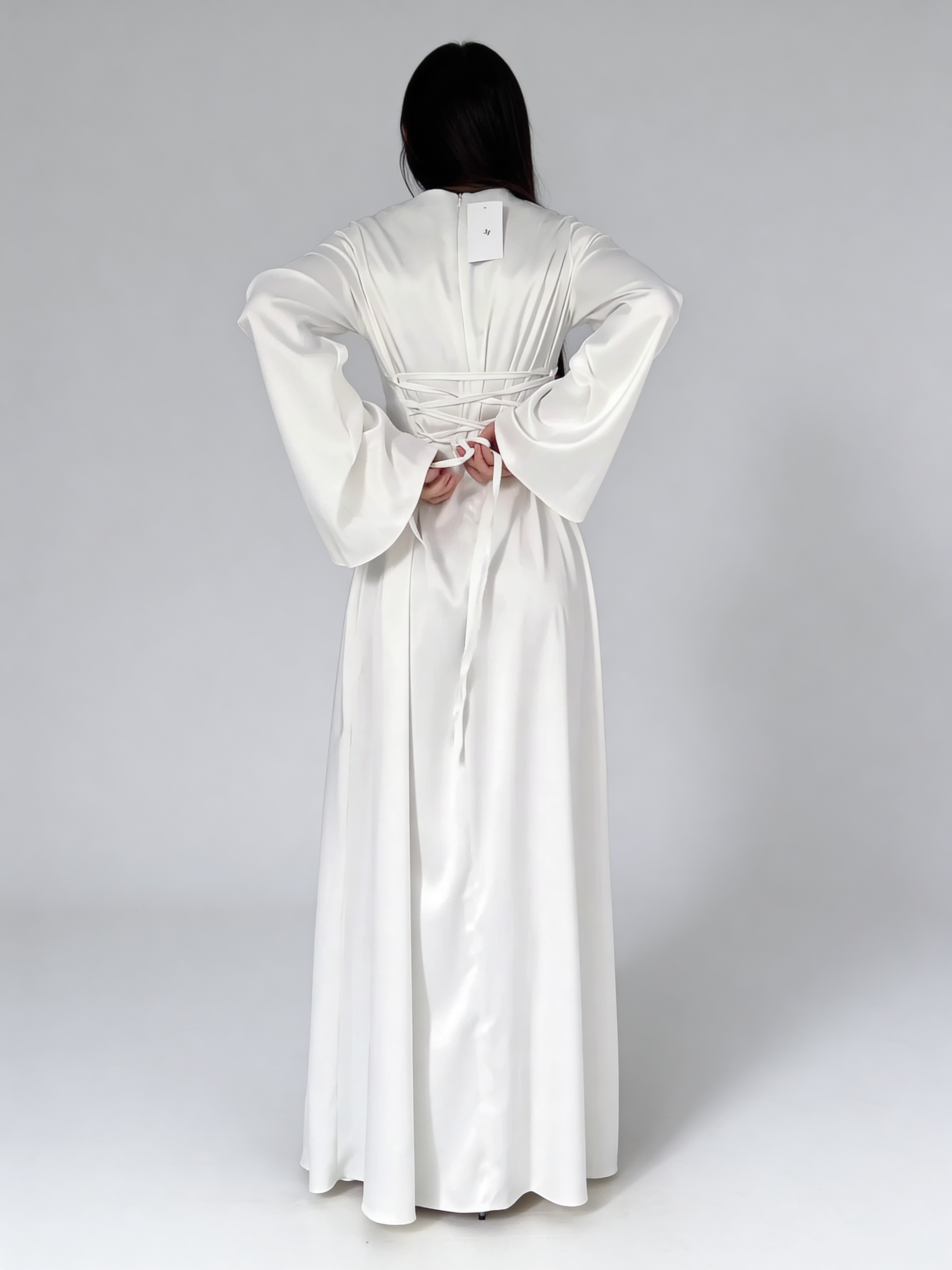 Vue de dos de la robe longue fluide en satin blanc, montrant la coupe fluide et la chute du tissu.