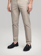 Mocassin Royal homme en cuir noir porté avec un pantalon beige élégant.