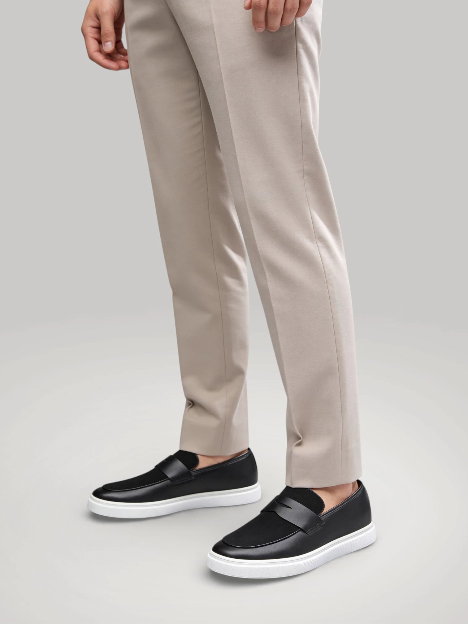 Gros plan de l'homme portant les mocassins noirs Le Flâneur Moderne avec un pantalon beige élégant.