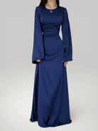 Femme portant la robe longue fluide à taille haute en bleu foncé satiné, style chic.