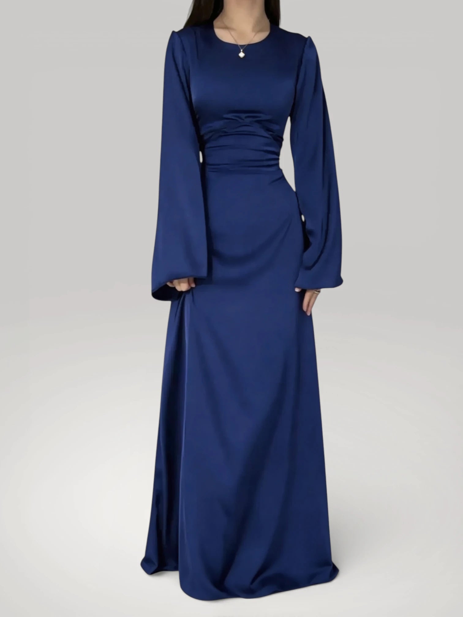 Femme portant la robe longue fluide à taille haute en bleu foncé satiné, style chic.