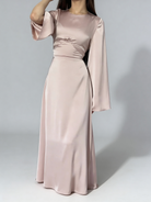 Femme portant la robe longue fluide à taille haute de couleur champagne, idéale voor une cérémonie.