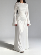 Femme portant la robe longue fluide en satin blanc, style chic et minimaliste.