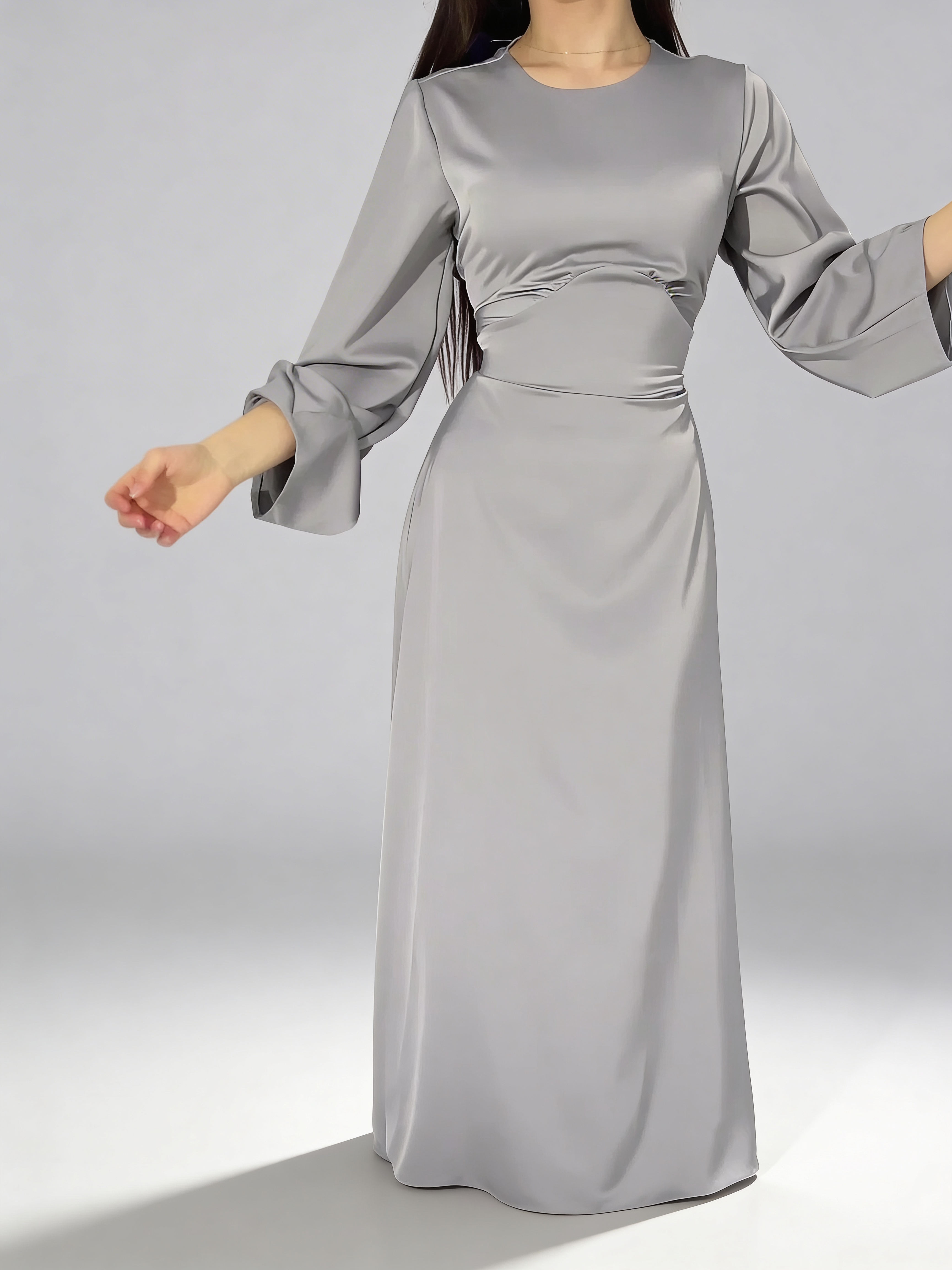 Détail du mouvement fluide de la robe longue en satin gris avec manches larges.