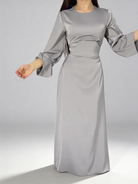 Détail du mouvement fluide de la robe longue en satin gris avec manches larges.