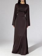 Femme portant la robe longue fluide à taille haute de couleur brun chocolat, coupe élégante.