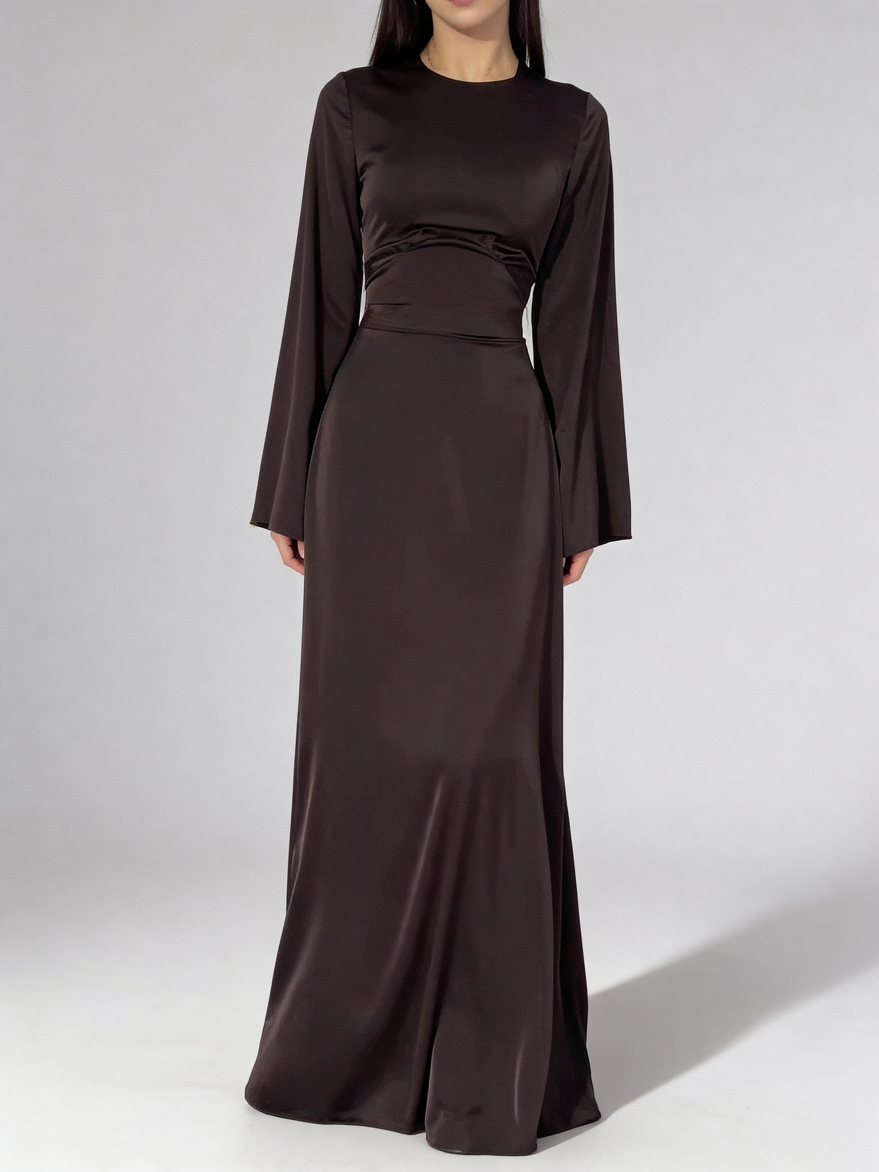 Femme portant la robe longue fluide à taille haute de couleur brun chocolat, coupe élégante.