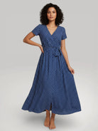 Robe longue d'été portefeuille pour femme de couleur bleue à pois blancs, portée par un mannequin - Modèle Julie par Urbain Couture.