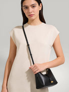 Sac à main demi-lune en cuir noir premium porté par un mannequin, design minimaliste avec détails dorés par Urbain Couture.