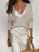 Urbain Couture beige gebreide trui over een crème satijnen midi-jurk met V-hals.